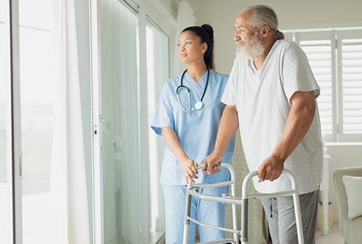 Skilled nursing woman standing with an elderly man